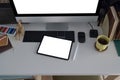 Creative designer workplace with digital tablet, computer, coffee cup and stationery on white table. Royalty Free Stock Photo