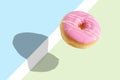Creative disposition of pink donut on bright background.