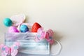 Creative Easter composition of coloful eggs, pink heart, butterflies and medical mask on light background, greeting card