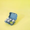 Creative Easter concept of cardboard box of eggs painted in silver aluminum foil and one cut in half and inside is kiwi fruit.