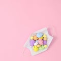 Creative Easter concept with colorful eggs in covid 19 frace mask on pastel pink background. Flat lay copy space minimal