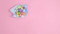 Creative Easter concept with colorful eggs in frace mask on pastel pink background. Flat lay copy space minimal layout