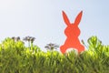Creative easter concept photo of red paper rabbit in the chamomile flowers and green grass on the blue sky background Royalty Free Stock Photo