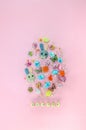 Creative Easter egg made with colorful candies, wooden buttons, flowers on pastel pink background. Flat lay Easter concept