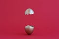 Creative Easter egg surprise concept. Golden easter egg broken in half on a red background, levitation. Copy space Royalty Free Stock Photo