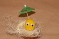 creative easter yellow egg with eyes under umbrella in decorative straw on vintage background, copy space Royalty Free Stock Photo