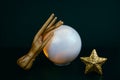 creative still life with a ball of predictions and two wooden female hands on a black background