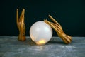 esoteric still life with a ball of predictions and two wooden female hands on concrete table against black wall Royalty Free Stock Photo