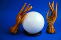 esoteric still life with a ball of predictions and two wooden female hands on a vibrant blue background Royalty Free Stock Photo