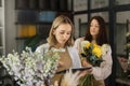 Creative female designer sit at desk in modern shop interior and make order for next period Royalty Free Stock Photo