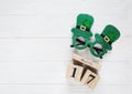 Creative festive St Patricks background with wooden calendar and glasses with shamrock on white wooden table.