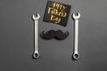 Creative flat lay composition with combination wrenches, card with phrase happy father`s day and retro stylish black paper photo