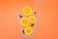 Creative flat lay composition made of orange slices, fresh mint leaves and cocktail straws on a bright orange background. Royalty Free Stock Photo