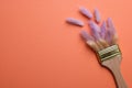 Creative flat lay composition with paint brush and fluffy wildflowers on coral background. Space for text