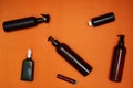Creative flat lay of dark cosmetic bottles on a bright orange background. Beauty blogger concept. Top view