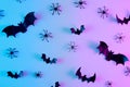 Creative flat lay Halloween background with bats silhouettes and spiders in vibrant gradient holographic neon colors