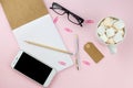 Creative flat lay photo of workspace desk with smartphone, eyeglasses, pen, pencil and notebook, minimal style on pink background. Royalty Free Stock Photo