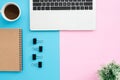 Creative flat lay photo of workspace desk. Top view office desk with laptop, clip, notebook, coffee cup and plant on blue pink Royalty Free Stock Photo