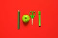 Creative flat lay of school supplies - green pens, pencils, scissors and an apple on a red background Royalty Free Stock Photo