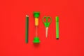 Creative flat lay of school supplies - green pens, pencils, scissors and hourglass on a red background Royalty Free Stock Photo