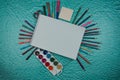 Creative flat lay of watercolor palettes, paint brushes, white paper. Artist workplace on a blue pastel background