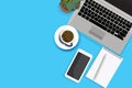 Creative flat lay of workspace desk. Top view office desk with laptop, notebooks, mobilephone and coffee cup on blue color