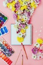 Creative flatlay of notebook with flowers and watercolors and brushes on pink