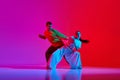 Creative flow. Young man and woman in motion, dancing hip hop against pink red background in neon light Royalty Free Stock Photo