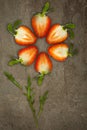 Creative flower made of strawberries cut from below lit on a stone background Food concept