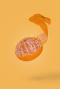 Creative food concept with fresh ripe peeled mandarin flying in air isolated on a yellow background