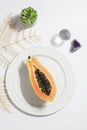 creative food concept with half papaya on plate with plant, crystals on white background.