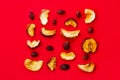 Creative food knolling. Slices of organic sun dried fruits dehydrated apples rose hips on red background. Healthy diet wholefoods