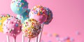 Colourful frosted cake pops with colourful sprinkles on vibrant pink background