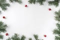 Creative frame made of Christmas fir branches on white background with red decoration, pine cones.