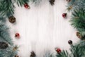 Creative frame made of Christmas fir branches on white wooden background with red decoration, pine cones. Xmas and New Year theme Royalty Free Stock Photo