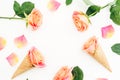 Creative frame made of roses flowers, petals and ice cream waffle cones on white background. Flat lay, top view. Royalty Free Stock Photo