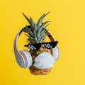 Creative funny pineapple face wearing glasses headphones and protective medical mask. Resting levitating pineapple face Royalty Free Stock Photo