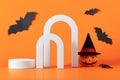 Creative Halloween composition with pumpkin, spiders, white podium and orange background. Modern Halloween aesthetic.