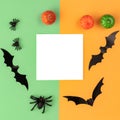 Creative Halloween composition. Pumpkins, bats, spiders and paper blank on orange and green background. Flat lay, top view, copy Royalty Free Stock Photo