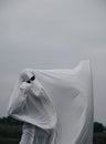 Creative Halloween costume for an adult. A ghost of a white sheet with black sunglasses dancing in an autumn field