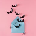 Creative Halloween horror concept with spiders, bats and paper envelope on pink background.