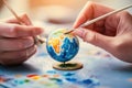 Creative hands paint a miniature globe representing global unity during a vibrant art session in a cozy studio Royalty Free Stock Photo