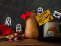 Creative Happy Halloween composition with pumpkin coffee cup, paper bats, autumn leaves, flowers on dark background