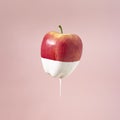 Creative healthy food concept of fruit dipped in white paint that flows down the fruit. Delicious sweet apple on pastel background