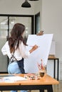 Creative hipster female artist painting on large canvas easel with oil colour Royalty Free Stock Photo