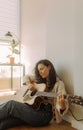 Creative hobby. Talented young female musician sit in armchair alone compose instrumental song using classic guitar. Copy space