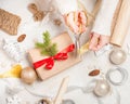 Creative hobby. Woman`s hands wrap christmas holiday handmade present in craft paper with twine ribbon. Making bow at xmas gift b Royalty Free Stock Photo