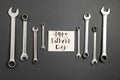 Creative holiday concept made with card with phrase happy father`s day, combination wrenches on grey and white background