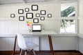 Creative home office interior with laptop blank screen, picture frame, chair, cup coffee, flower pot on desk Royalty Free Stock Photo