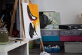 Creative home studio: easel with started painting, paper, painting supplies.
